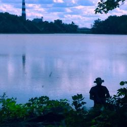 People looking at lake against sky