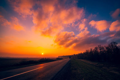 Road by sea against romantic sky at sunset