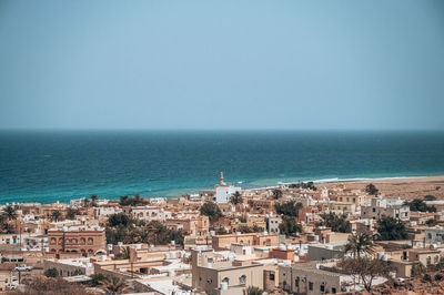 High angle view of townscape by sea against clear sky