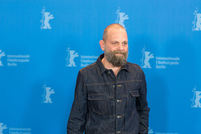 Mid adult man standing against blue background