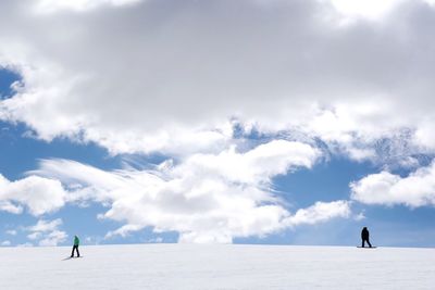 People skiing on snow against sky