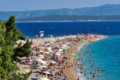 Crowd on sea by mountain