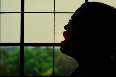 Close-up of silhouette man by window