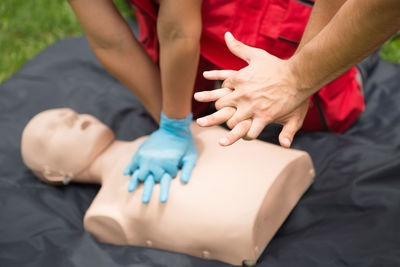 Cropped hands of man instructing paramedic practicing cpr on dummy