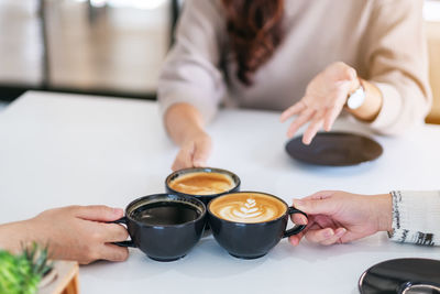 Midsection of woman holding coffee cup on table