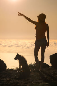 Silhouette man with dog on beach during sunset