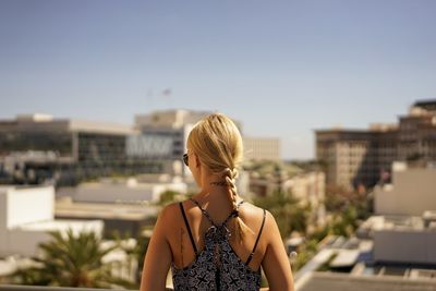 Rear view of woman standing against sky in city