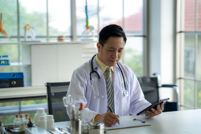 Side view of young man using mobile phone in office