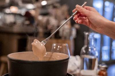 Female tourist dipping food in cheese fondue at table in restaurant