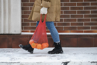 Happy woman carry reusable bag with oranges from the shop. walking outdoors in winter. festive