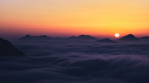 Scenic view of dramatic sky over silhouette mountains during sunset