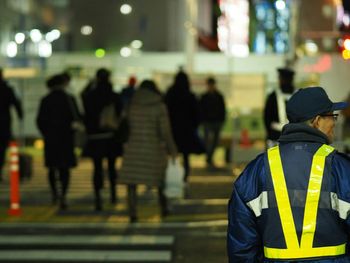 Police officer standing against people crossing on road in city