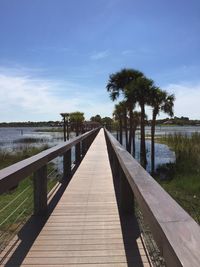 Narrow empty walkway against blue sky