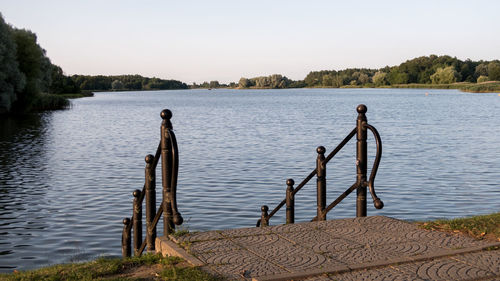 Wooden posts in lake against clear sky