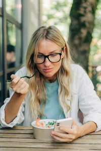 Business woman during lunch uses mobile phone for social media.