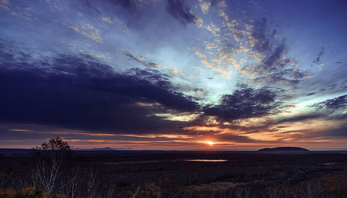 Scenic view of dramatic sky over land during sunset