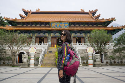 Woman standing outside temple against building