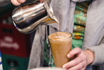 Midsection of woman pouring coffee in glass at coffee shop