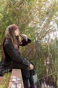 Side view of man sat by edge of water. with prop bottle.