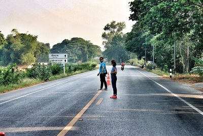 Full length side view of people walking on road