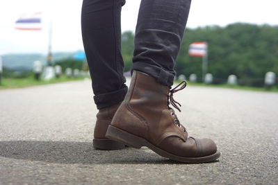 Low section of man wearing leather shoe standing on road
