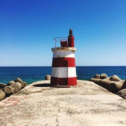 Lighthouse on beach against clear sky