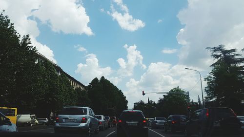 Cars on street in city against sky