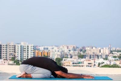 Man relaxing in city against clear sky