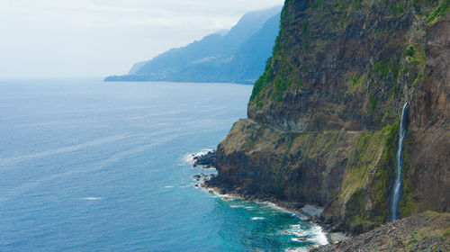 Scenic view of sea by mountains against sky