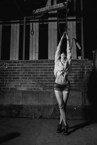 Female model posing against wall at night