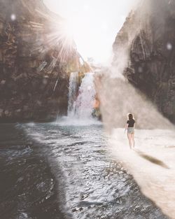 Woman splashing water at waterfall