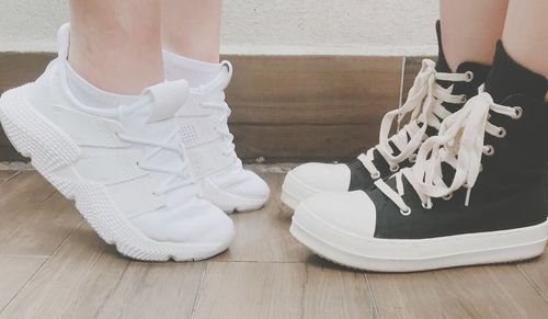 Low section of people wearing shoes while standing on hardwood floor at home