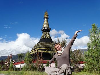 Portrait of woman with arms outstretched with buddhist stupa in background at samye monastery