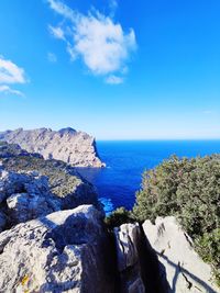 Rocks by sea against blue sky