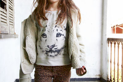 Portrait of young woman standing against wall