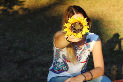 High angle view of woman holding sunflower on field