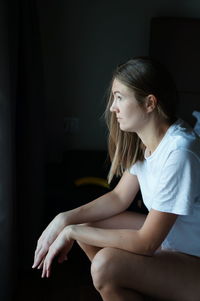 Side view of a young woman sitting at home