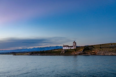 Lighthouse by sea against sky