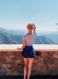 Rear view of woman standing on mountain against sky