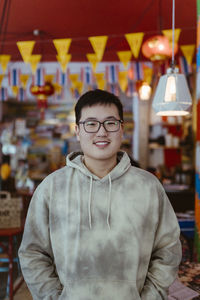Portrait of smiling young man wearing hoodie at restaurant