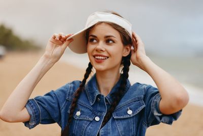 Portrait of young woman standing against sky