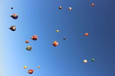 Tilt image of hot air balloons flying against clear sky