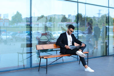 Side view of businessman using laptop while sitting on railing
