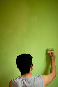 Side view of woman holding drink against orange background