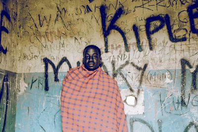 Portrait of man standing against graffiti wall