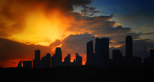 Silhouette buildings against sky at sunset