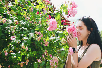 Portrait of young woman standing by plants