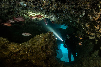 Illuminated light amidst water against rock