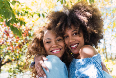 Closeup of two delighted happy female afro american friends hugging and smiling