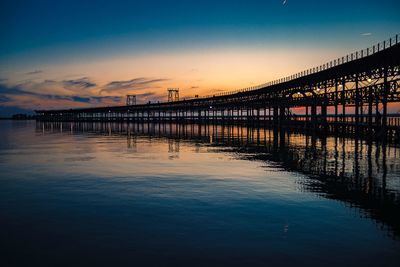 Bridge over sea against sky during sunset